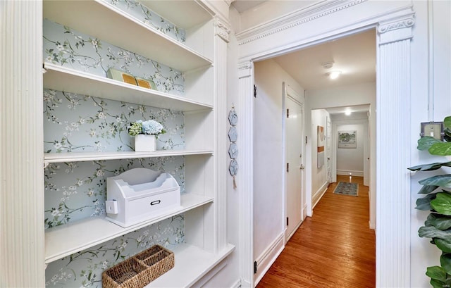 hall with wood finished floors and wallpapered walls