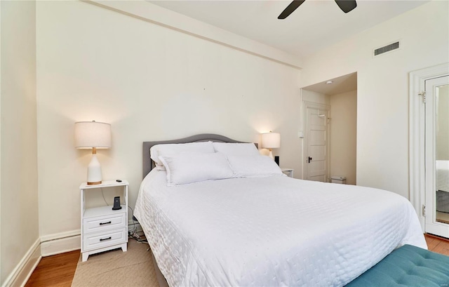 bedroom with ceiling fan, wood finished floors, visible vents, and baseboards