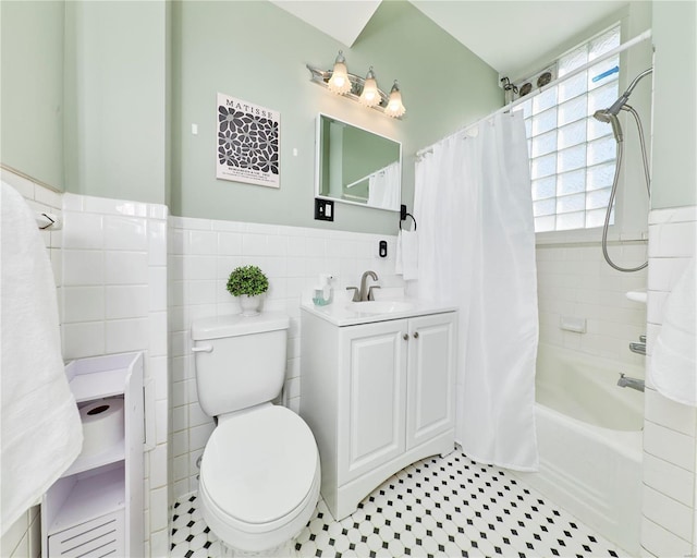 bathroom with vanity, a wainscoted wall, shower / bath combo, tile walls, and toilet