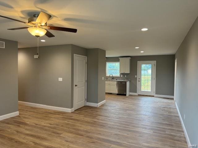 unfurnished living room featuring light wood-type flooring, ceiling fan, and sink