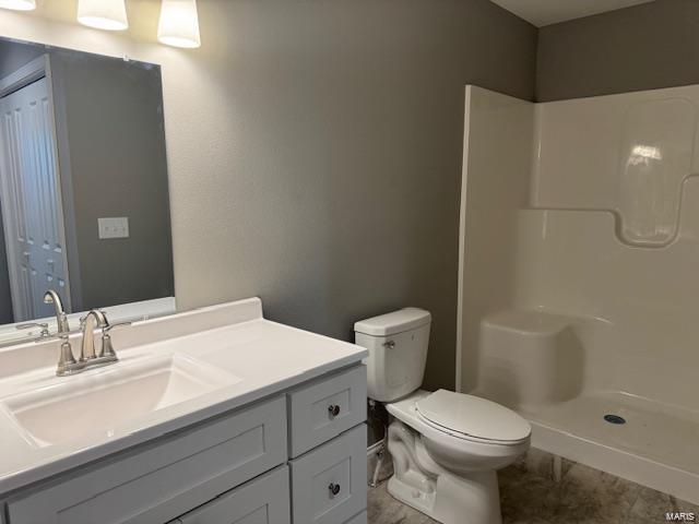 bathroom featuring toilet, walk in shower, and vanity