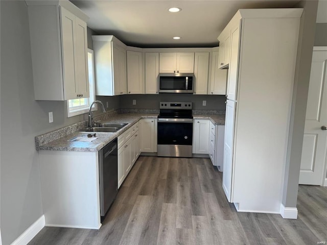 kitchen featuring sink, stainless steel appliances, light hardwood / wood-style flooring, and white cabinetry