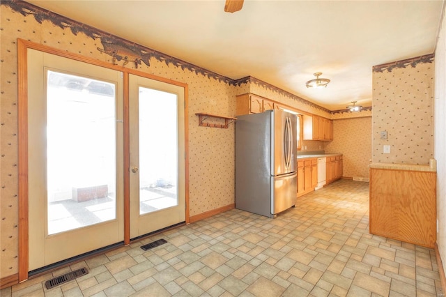 kitchen with stainless steel fridge, white dishwasher, and light brown cabinetry