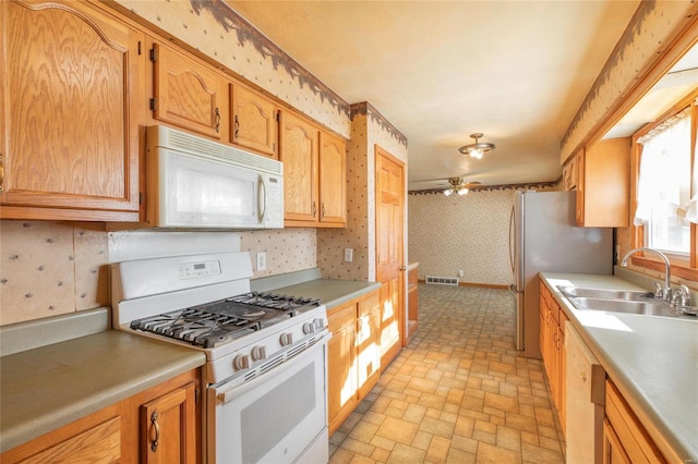 kitchen featuring white appliances, ceiling fan, and sink