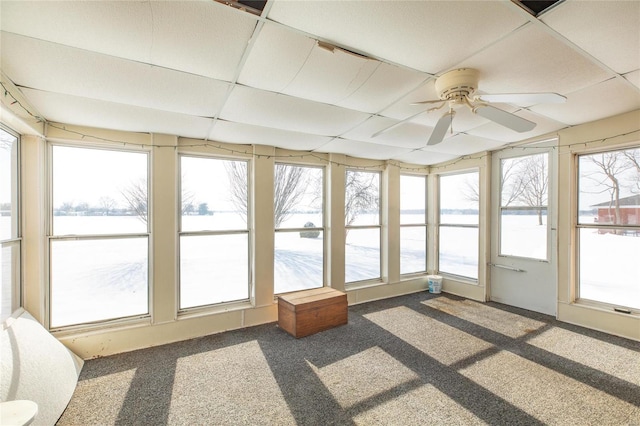 unfurnished sunroom featuring ceiling fan, a drop ceiling, and a healthy amount of sunlight