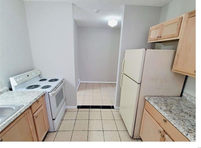 kitchen with light brown cabinets, white appliances, light tile patterned floors, a textured ceiling, and light stone counters