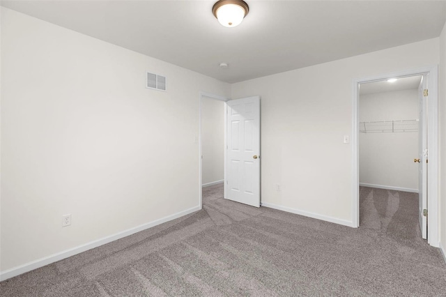 unfurnished bedroom featuring carpet flooring, a spacious closet, and a closet