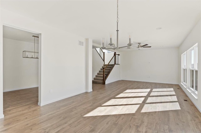 interior space with ceiling fan with notable chandelier and light wood-type flooring