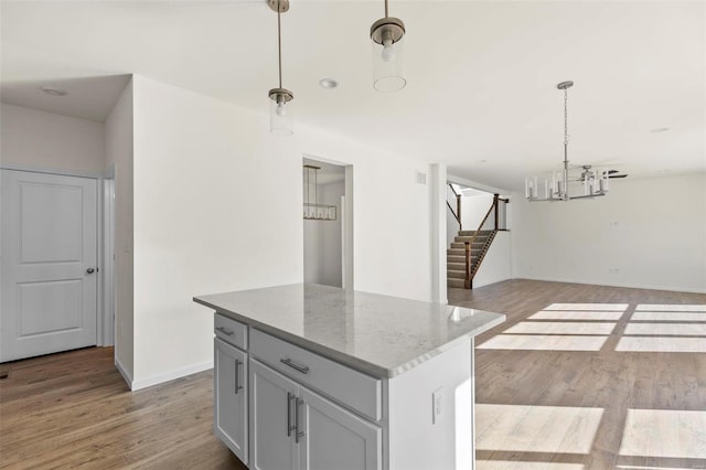 kitchen with light stone countertops, light hardwood / wood-style floors, and hanging light fixtures