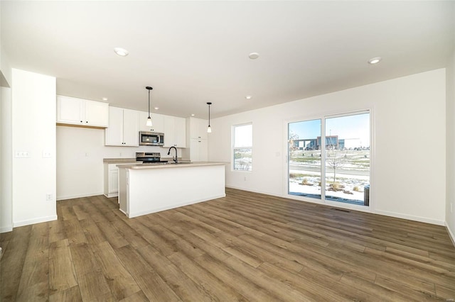 kitchen featuring sink, white cabinets, hanging light fixtures, a kitchen island with sink, and stainless steel appliances