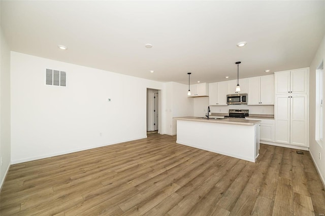 kitchen with white cabinetry, stainless steel appliances, and an island with sink