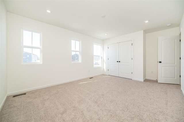 unfurnished bedroom with light colored carpet and a closet