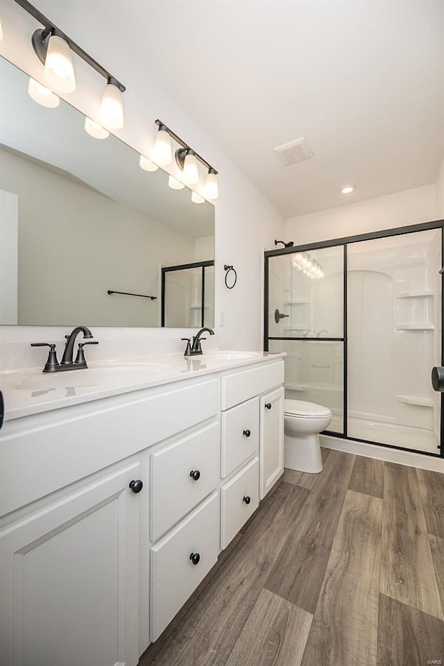 bathroom with vanity, hardwood / wood-style flooring, a shower with shower door, and toilet