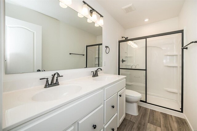 bathroom featuring vanity, hardwood / wood-style floors, a shower with door, and toilet