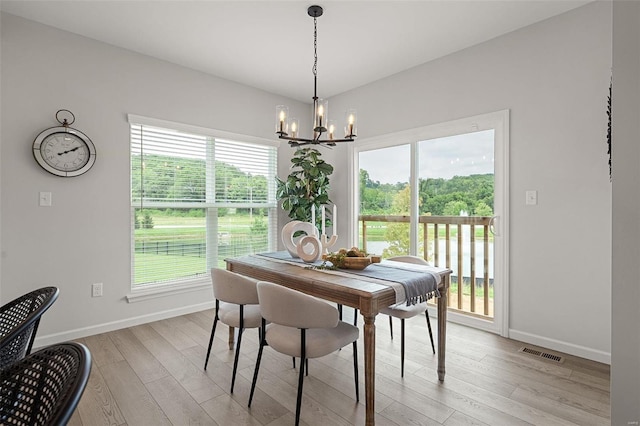 dining space with light wood-type flooring and an inviting chandelier