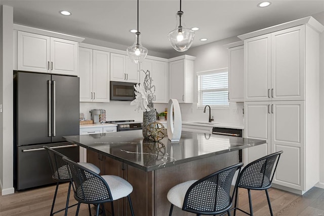 kitchen with high end fridge, light hardwood / wood-style flooring, white cabinets, a kitchen island, and hanging light fixtures