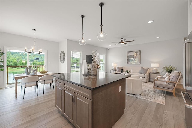 kitchen with ceiling fan with notable chandelier, light hardwood / wood-style flooring, a kitchen island, and decorative light fixtures