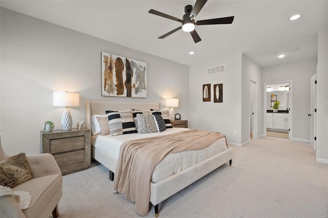 carpeted bedroom with ensuite bath and ceiling fan