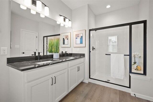 bathroom with hardwood / wood-style floors, vanity, and a shower with door