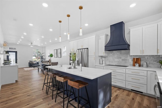 kitchen with custom exhaust hood, black electric stovetop, tasteful backsplash, and stainless steel fridge