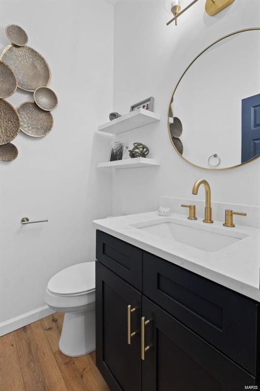 bathroom featuring toilet, vanity, baseboards, and wood finished floors