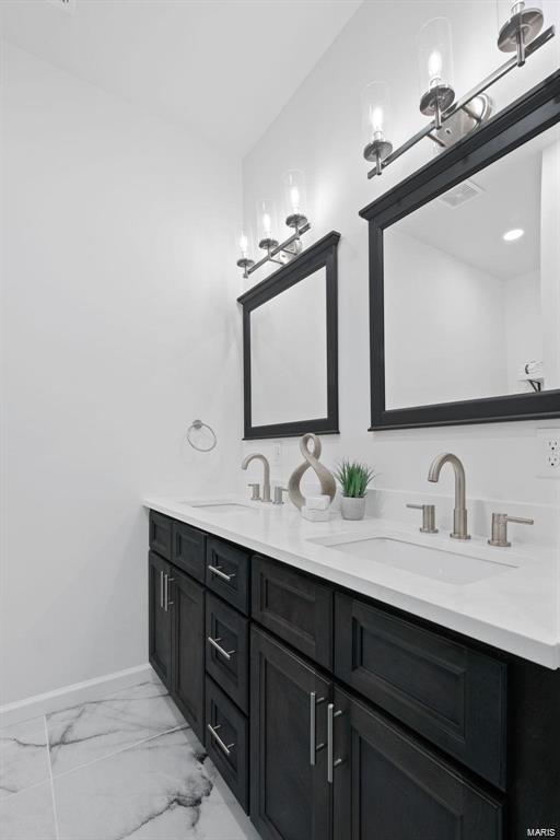 bathroom featuring a sink, baseboards, marble finish floor, and double vanity