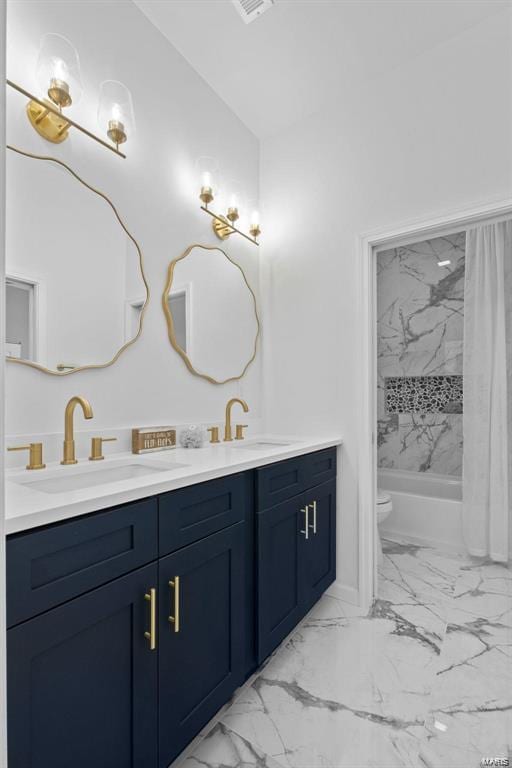 full bathroom with double vanity, toilet, marble finish floor, and a sink