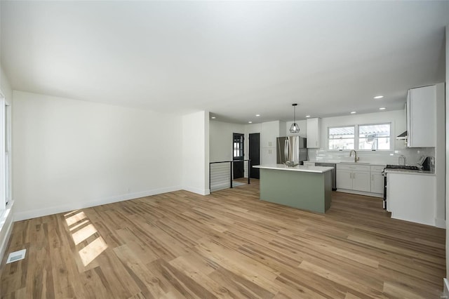 kitchen featuring decorative backsplash, stainless steel fridge, a center island, light hardwood / wood-style floors, and hanging light fixtures