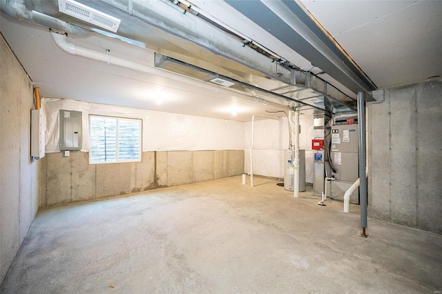 basement with heating unit, electric panel, and water heater