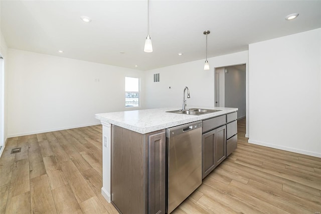 kitchen with stainless steel dishwasher, sink, dark brown cabinets, pendant lighting, and an island with sink