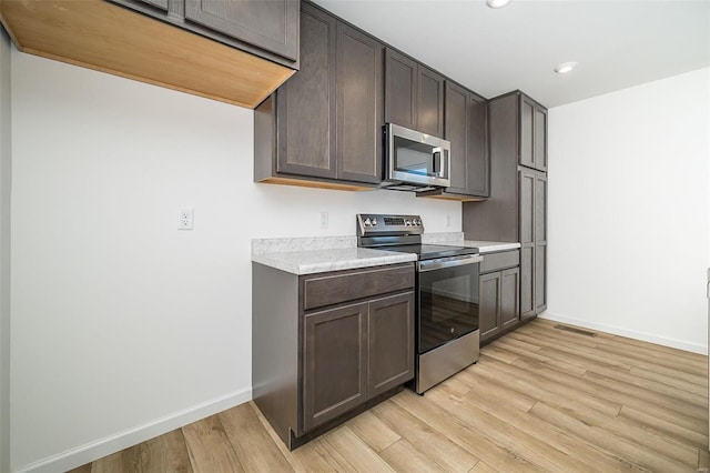 kitchen with light hardwood / wood-style floors, dark brown cabinets, and stainless steel appliances