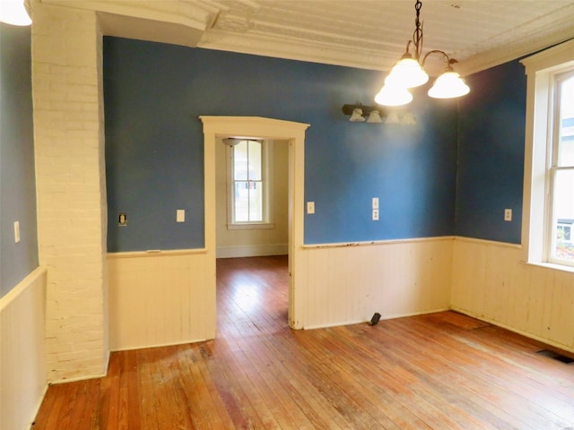 spare room featuring hardwood / wood-style floors, crown molding, and an inviting chandelier