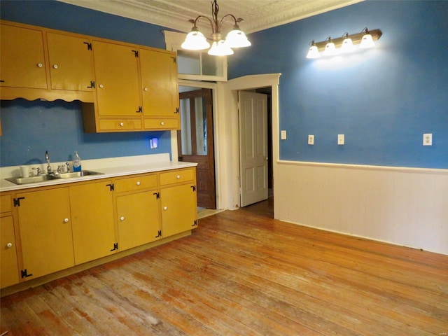 kitchen featuring crown molding, sink, light hardwood / wood-style flooring, a notable chandelier, and hanging light fixtures