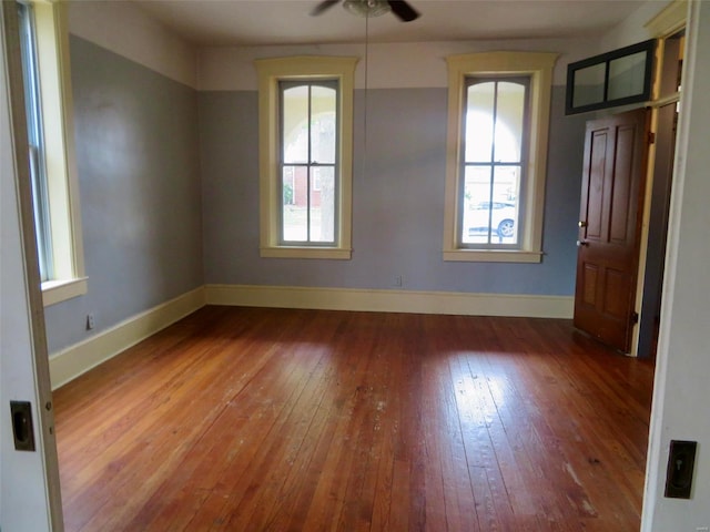 empty room with ceiling fan, plenty of natural light, and hardwood / wood-style flooring