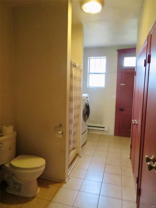 bathroom with a shower with shower curtain, washer / dryer, toilet, and a baseboard heating unit