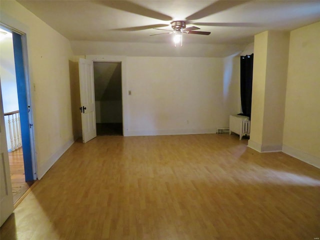 unfurnished room featuring ceiling fan, radiator heating unit, and light hardwood / wood-style flooring