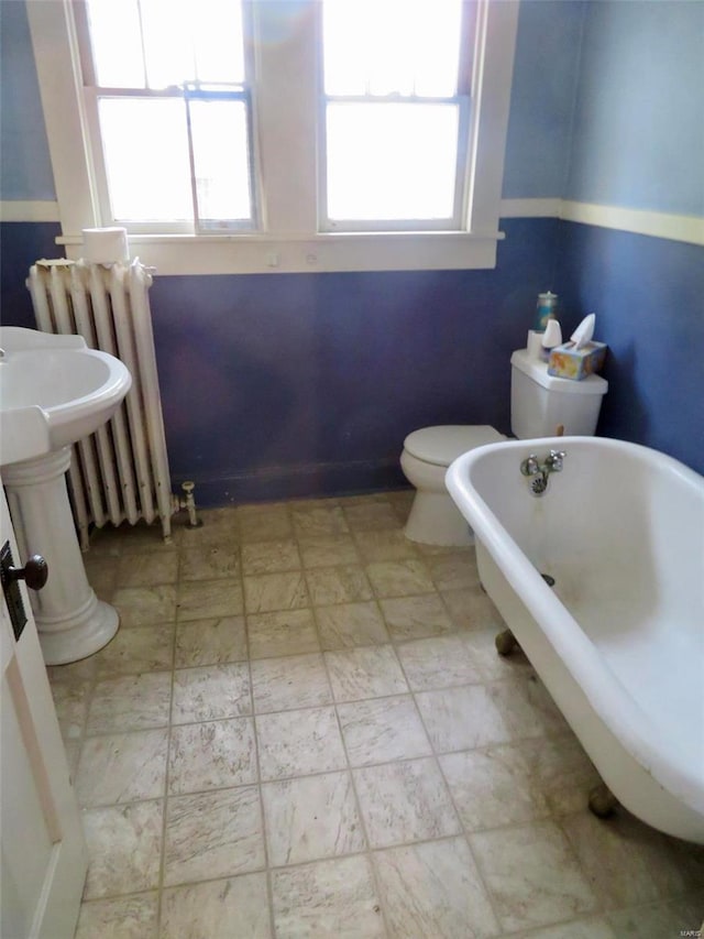 bathroom featuring radiator heating unit, a bath, and toilet