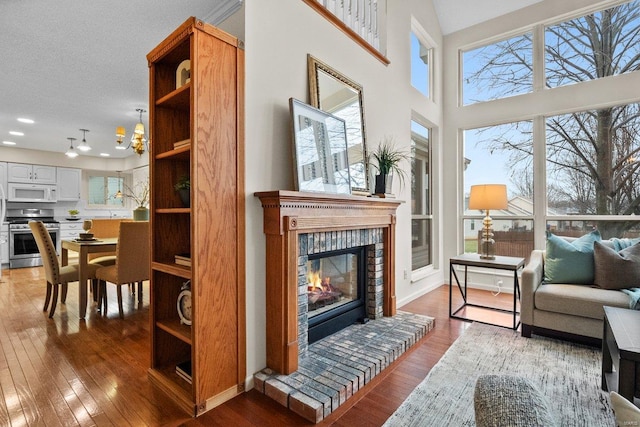 sitting room with a textured ceiling, hardwood / wood-style floors, a brick fireplace, and a notable chandelier