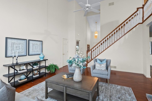 living room featuring dark hardwood / wood-style floors, ceiling fan, and a high ceiling