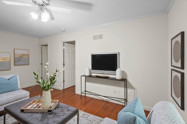 living room featuring crown molding, wood-type flooring, a textured ceiling, and ceiling fan