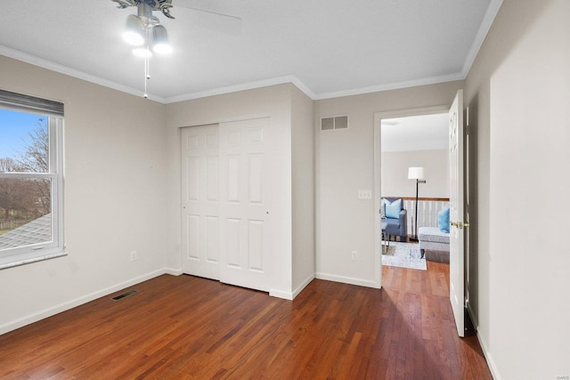 unfurnished bedroom featuring crown molding, ceiling fan, dark hardwood / wood-style flooring, and a closet