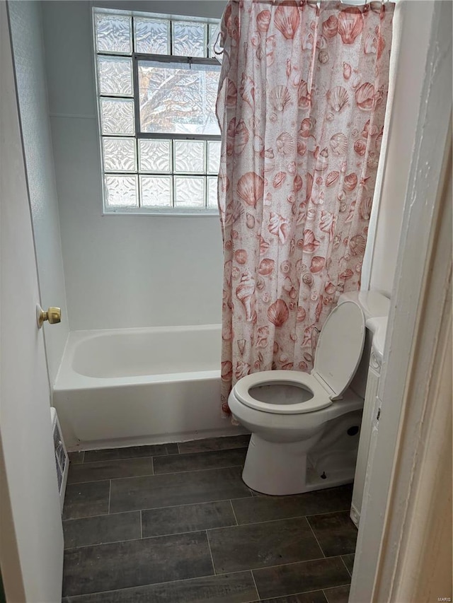 bathroom featuring toilet, shower / bathtub combination with curtain, and a healthy amount of sunlight