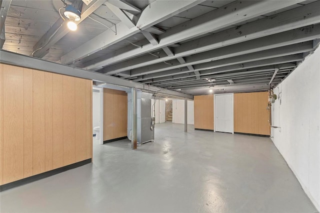 basement featuring heating unit and wood walls