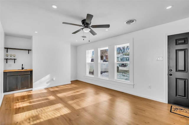 unfurnished living room featuring light hardwood / wood-style flooring, ceiling fan, and sink