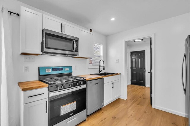 kitchen with white cabinetry, butcher block counters, sink, and appliances with stainless steel finishes