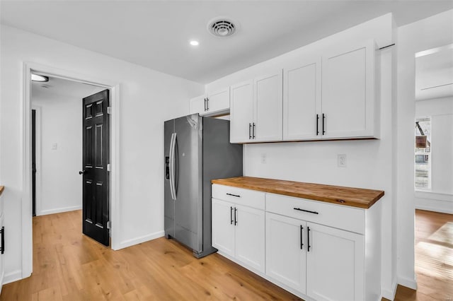 kitchen with white cabinetry, butcher block counters, stainless steel fridge, and light wood-type flooring