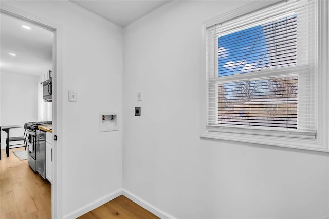 clothes washing area featuring light hardwood / wood-style floors, washer hookup, and hookup for an electric dryer