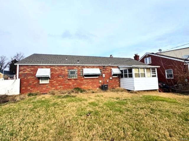 rear view of house featuring a lawn and a sunroom