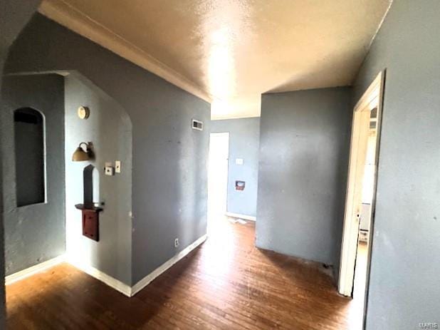 hallway with ornamental molding and dark wood-type flooring