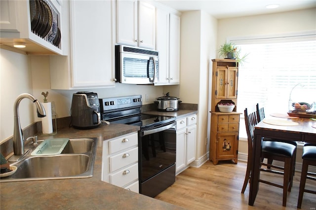 kitchen with white cabinets, light hardwood / wood-style floors, sink, and black electric range